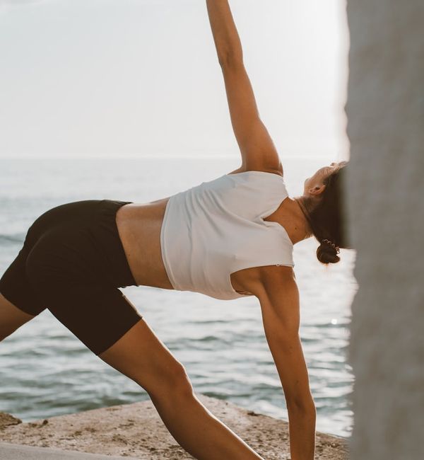 Person feeling energized and stretching outdoors at sunrise.